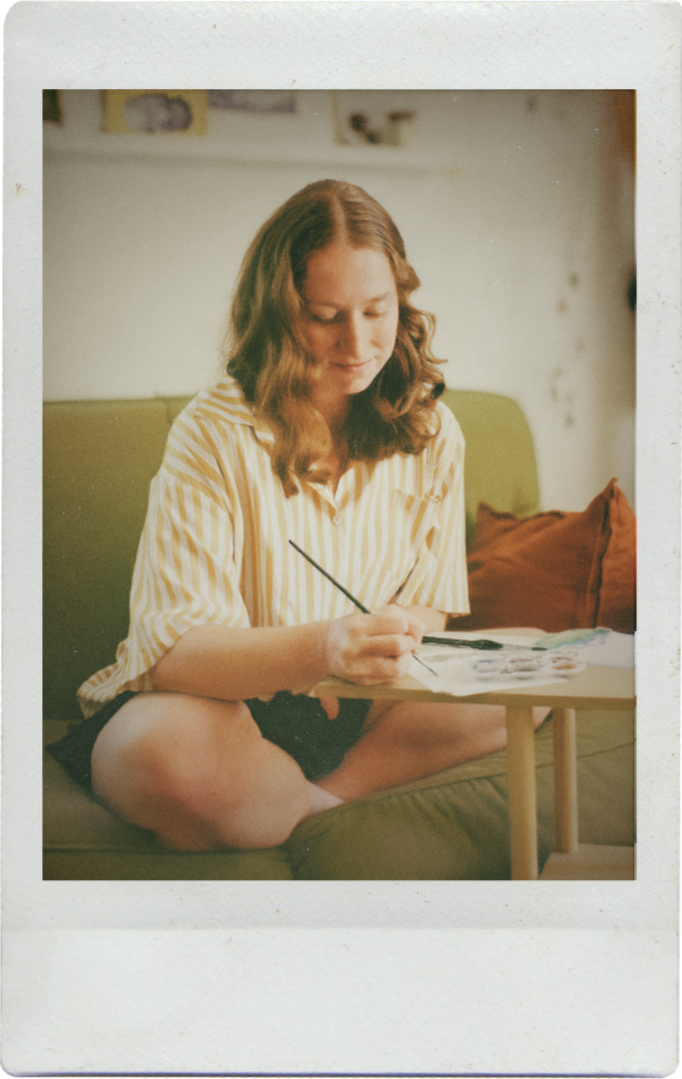 About Me Photo of Amy, watercolor artist behind Fablefern Studio, sitting and painting invitations.